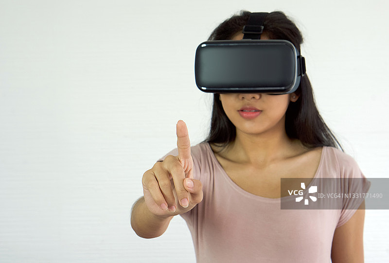 亚洲青少年使用虚拟现实眼镜选择菜单在互动游戏。未来科技的概念。图片素材