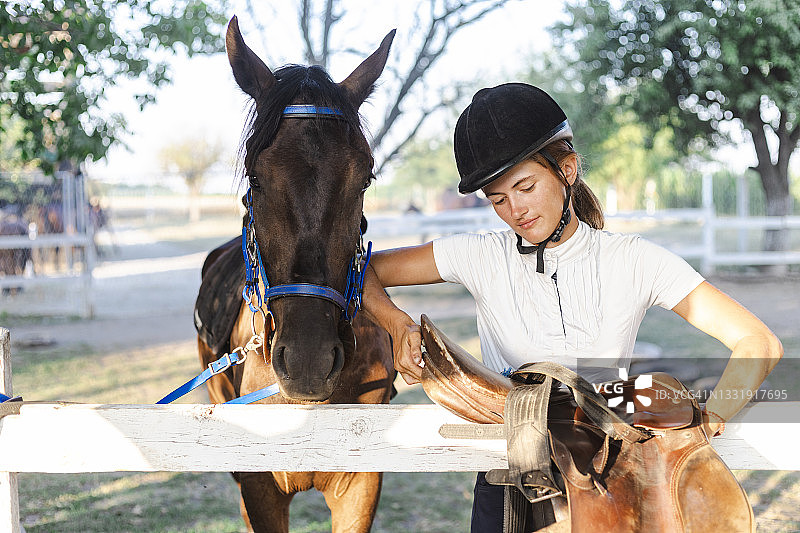 漂亮的年轻女人穿着骑马服抚摸着她的马图片素材