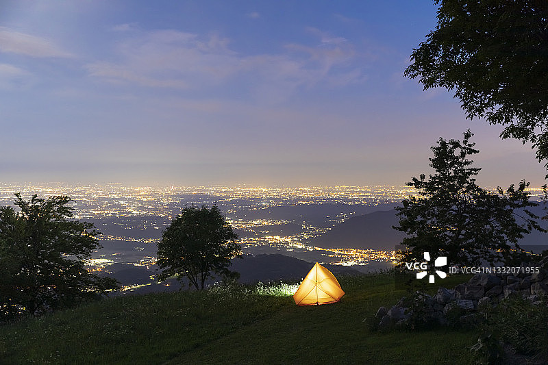 山顶上的照明露营帐篷，下面的城市夜景图片素材