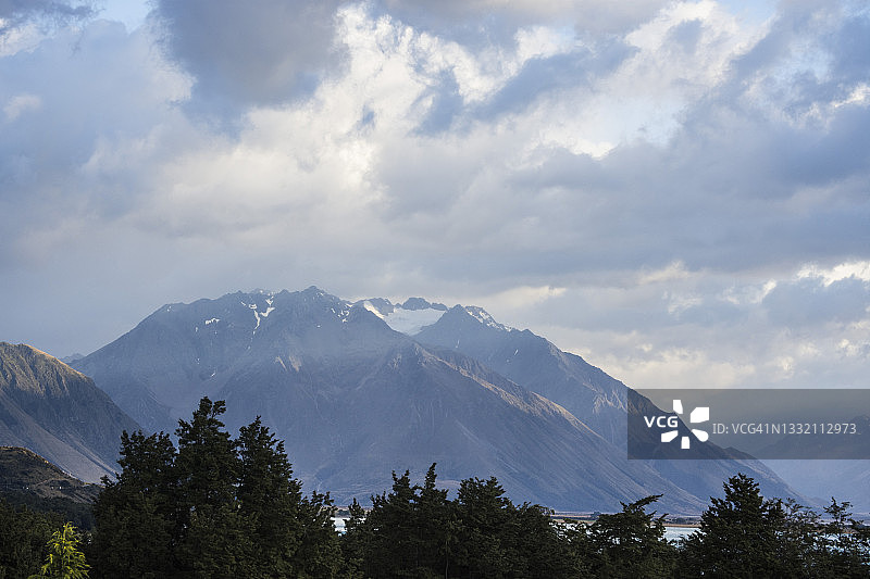 在一个阴天，前景是白雪皑皑的高山和松树图片素材