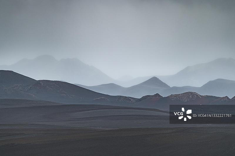 黑色熔岩沙漠，火山口，烟雾中的山脉，Tungnaa，冰岛高地，Sudurland，冰岛图片素材