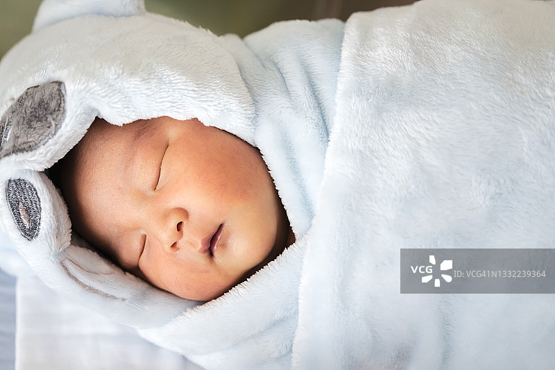 刚出生的婴儿在家里穿着婴儿大衣睡觉。宝宝和母亲节的概念。图片素材