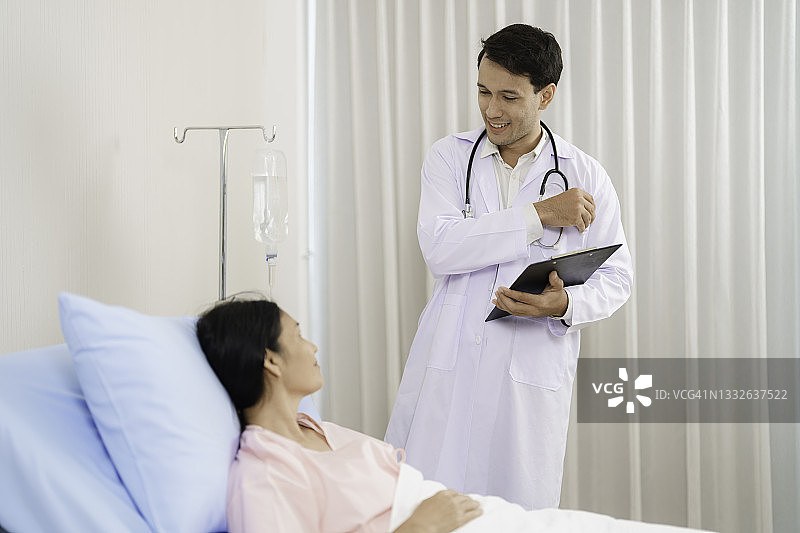 男医生在病房探望女病人。图片素材