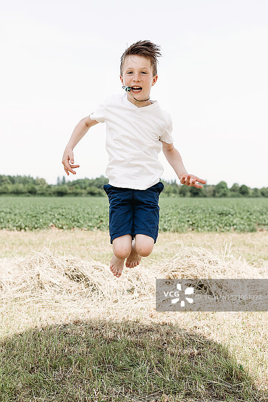 一个男孩在草地上高兴地跳着图片素材