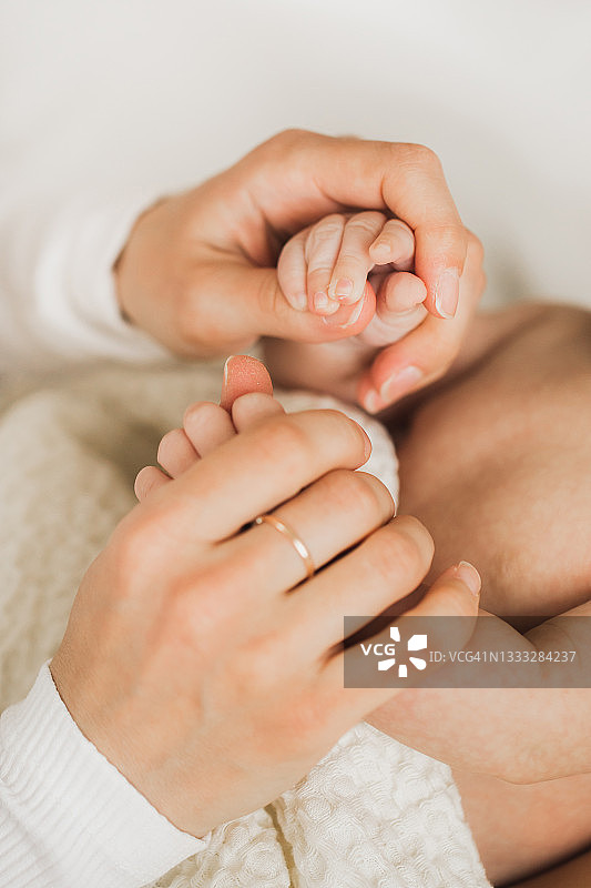 妈妈和宝宝轻轻摸着手。图片素材