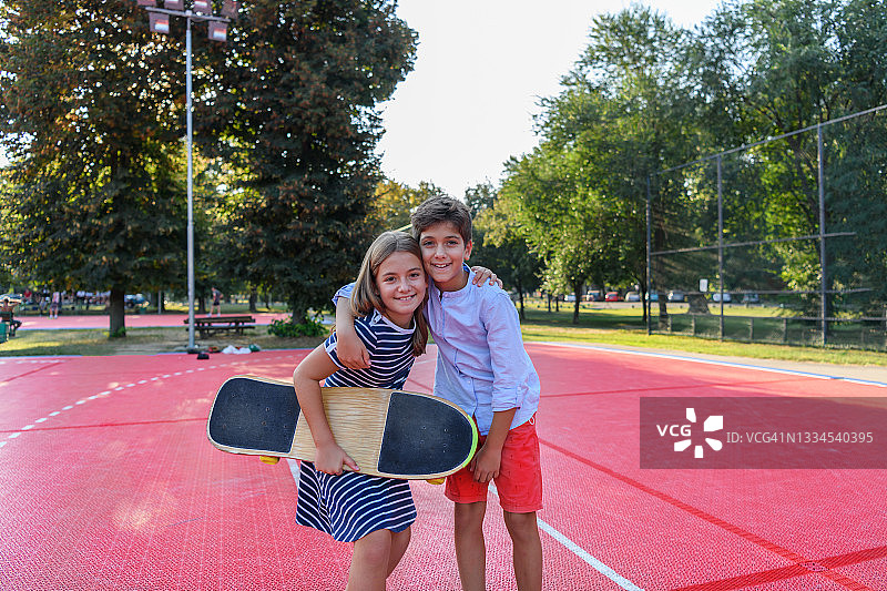 可爱的小孩子站在公园里玩滑板。图片素材