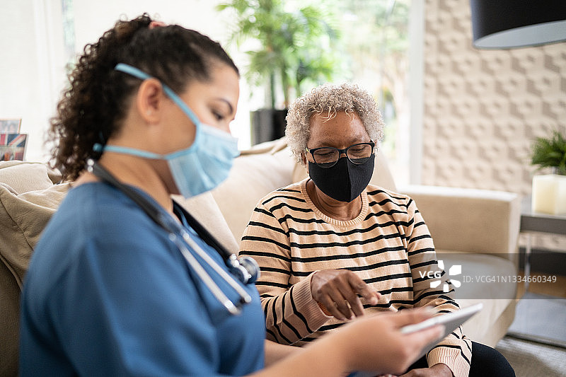 一位年长的妇女戴着防护口罩在出诊时与护士交谈图片素材