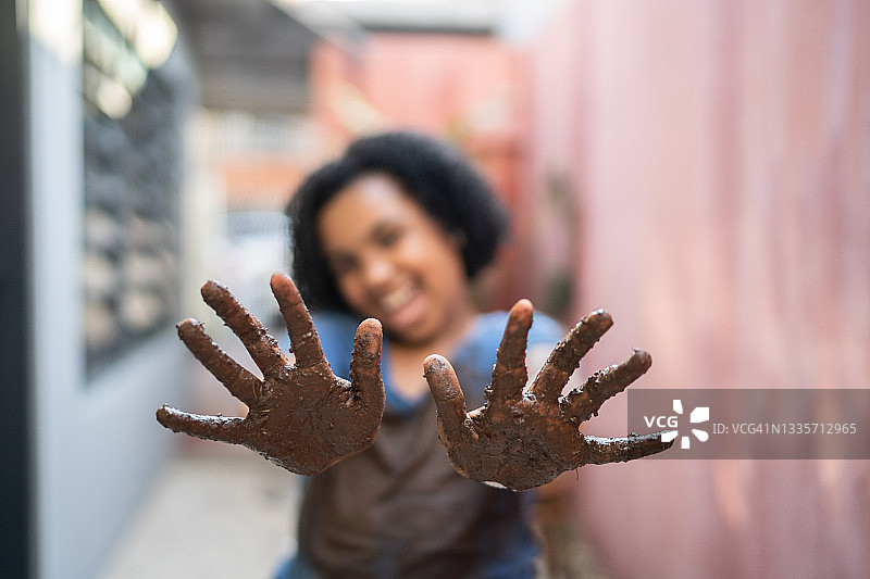 一个女孩的肖像，她的手被泥土和脏衣服弄脏了图片素材