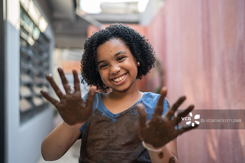 一个女孩的肖像，她的手被泥土和脏衣服弄脏了图片素材