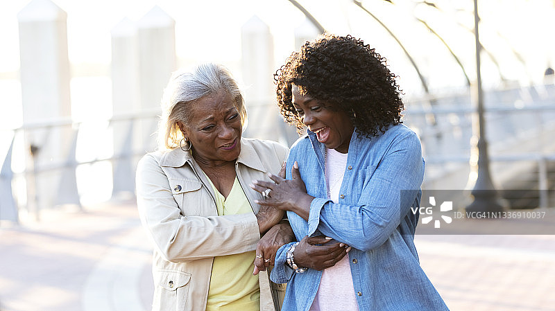 老年非洲裔美国妇女挽着胳膊笑着走图片素材