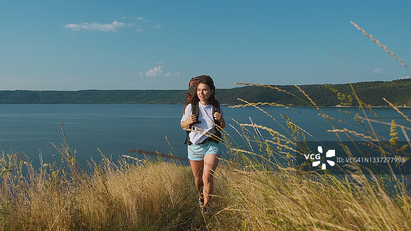 那位年轻女子背着背包沿着美丽的海岸徒步旅行图片素材