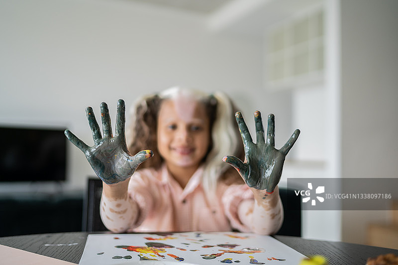 花斑女孩的肖像，在家里上色后，露出五彩缤纷的双手图片素材