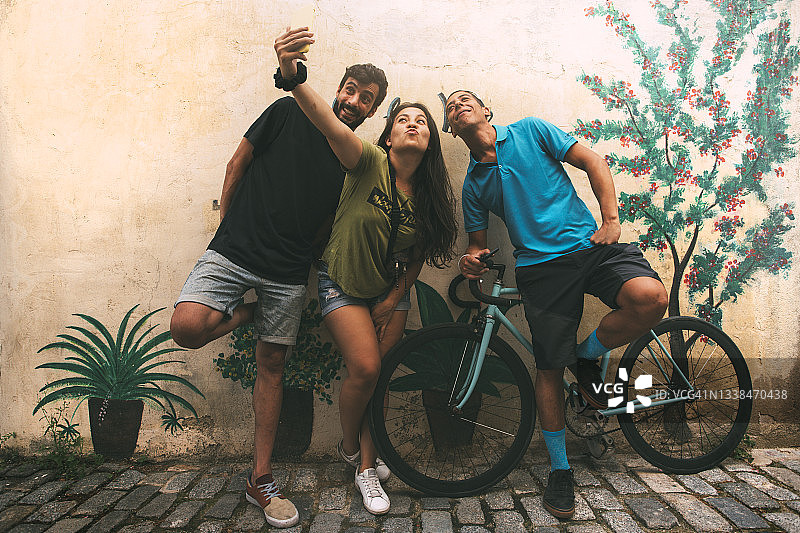 一群快乐微笑的朋友在街上用手机自拍。一群年轻人正在用智能手机拍照。copyspace。图片素材