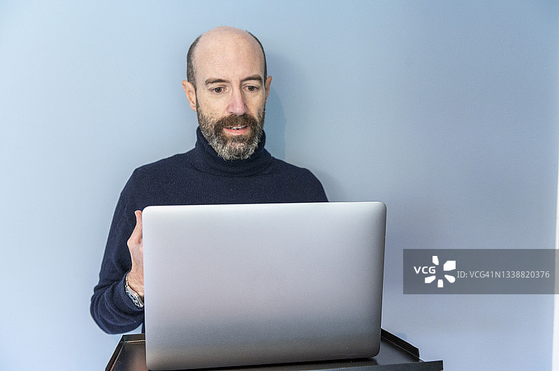 英国，萨里，一名男子正在通过笔记本电脑进行虚拟会议图片素材