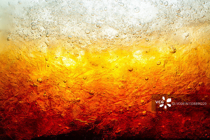黑色可乐背景下的冰块特写。夏日清凉甜饮的质感，玻璃壁上有泡沫和宏观气泡。嘶嘶作响或浮上水面图片素材