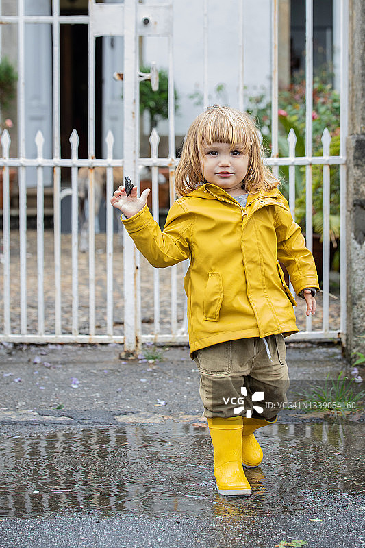 小女孩在下雨天玩得很开心。图片素材