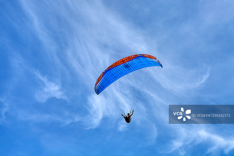 在一个阳光明媚的春天，滑翔伞飞过山坡。假日休闲体育活动图片素材