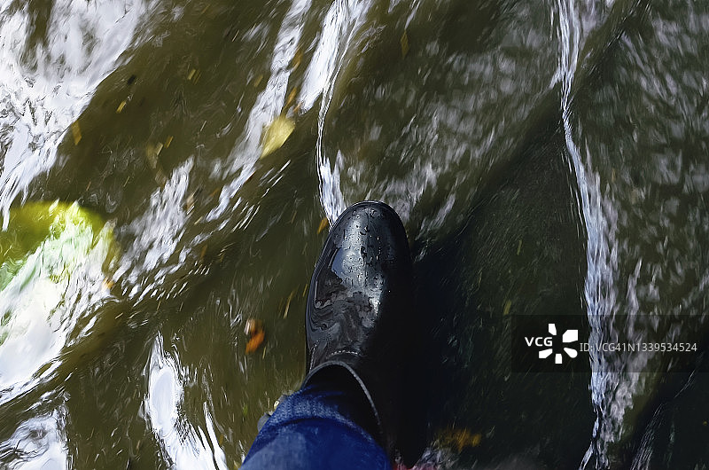 下雨天，人们穿着长筒靴走在水坑里，特写镜头。图片素材