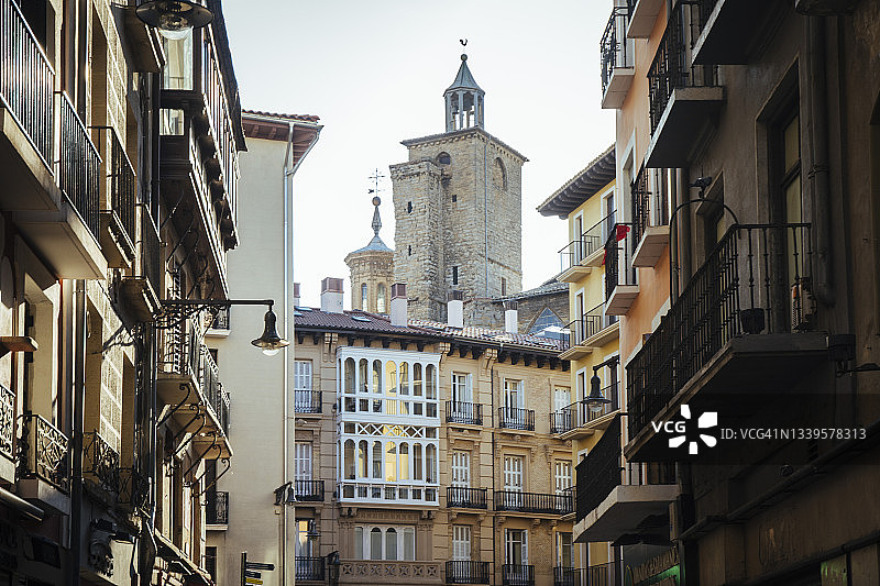 从西班牙潘普洛纳一条狭窄的城市街道上俯瞰历史悠久的钟楼图片素材