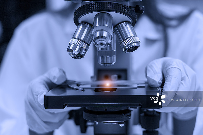 实验室概念:科学家在实验室使用显微镜进行测试的特写照片。图片素材