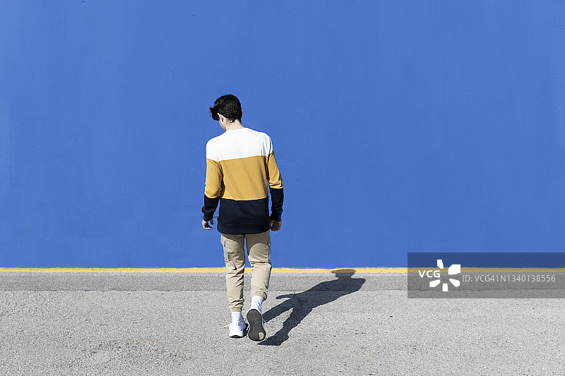 一个年轻男性靠在蓝色墙上的后视镜图片素材