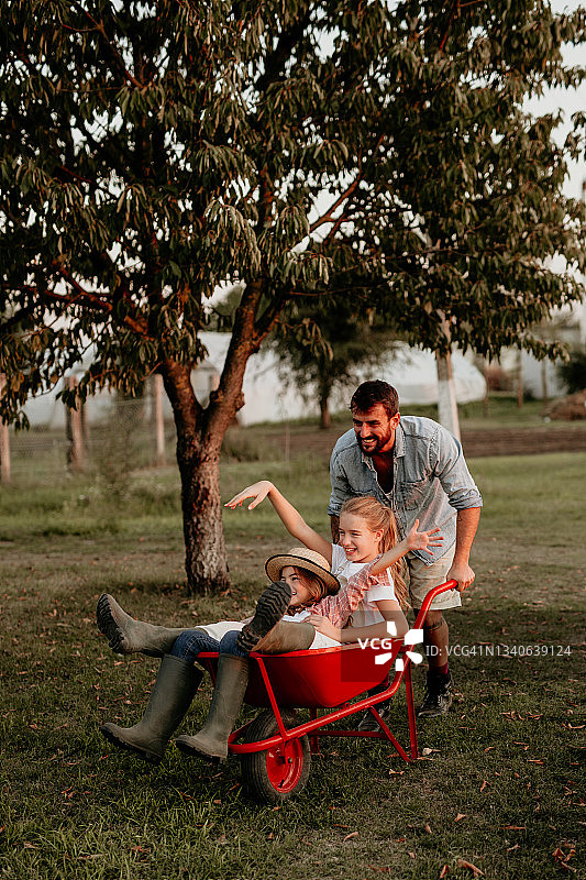 幸福的家庭在农场的独轮手推车上图片素材