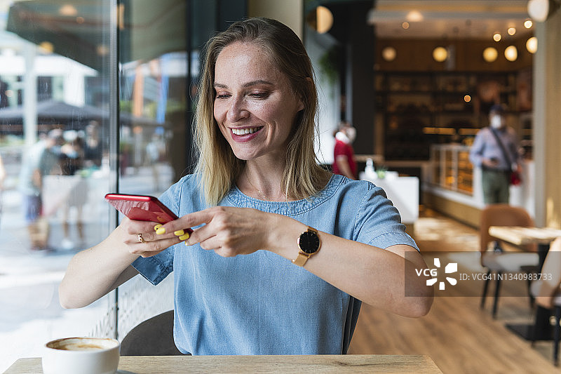 女商人在咖啡馆用智能手机拍咖啡杯图片素材