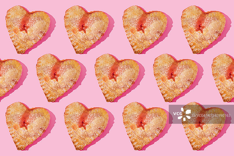 图案小心形甜馅饼平放在粉红色的背景图片素材