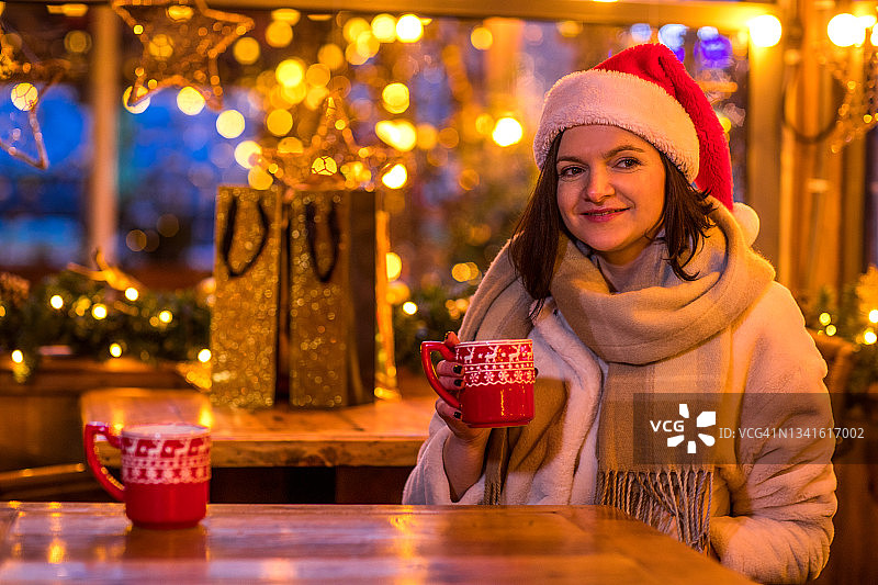 一个美丽的女人在一个温暖的装饰咖啡馆在冬天图片素材