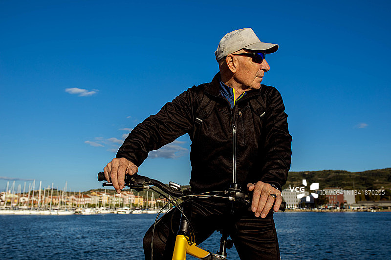 活跃的老年男性游客从他的自行车看海的观点图片素材