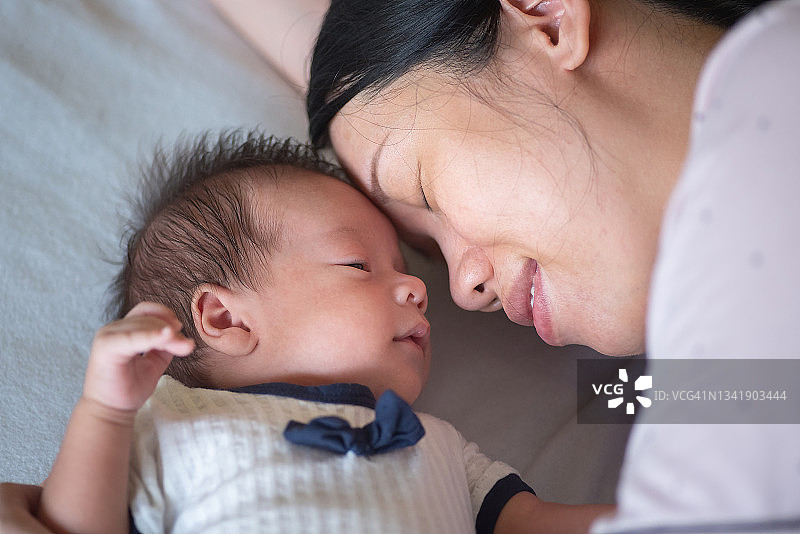 当婴儿躺在床上的时候，妈妈和刚出生的小男孩有一个可爱的时刻图片素材