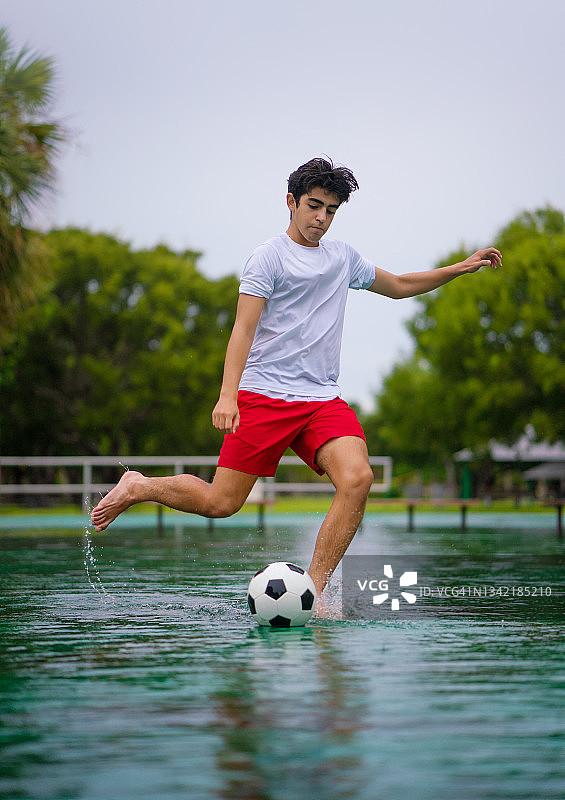 在公园里踢足球的青少年在雨后被洪水淹没图片素材