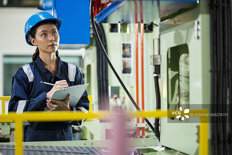 机器安全检查表及防护设备。年轻的女工程师在一家工业工厂检查机械。图片素材