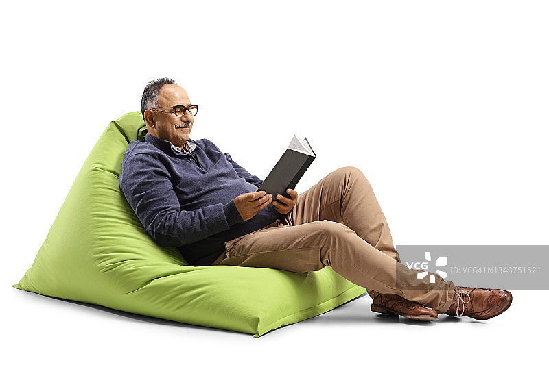 一个成熟的男人坐在绿豆袋上看书图片素材