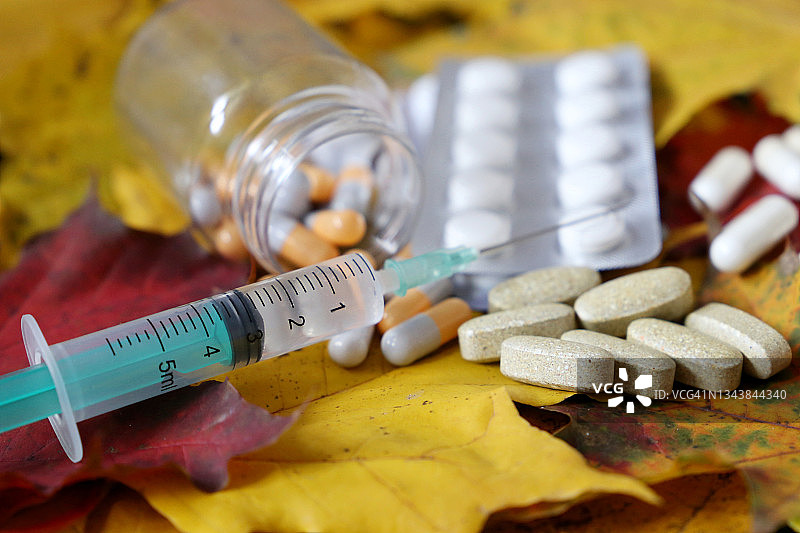 注射器和药丸在秋天的枫叶图片素材