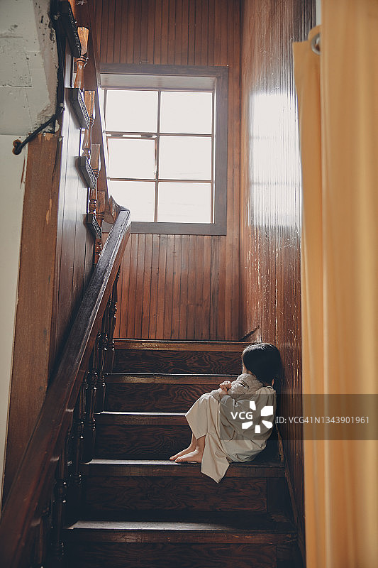 一个孩子独自坐在楼梯上图片素材