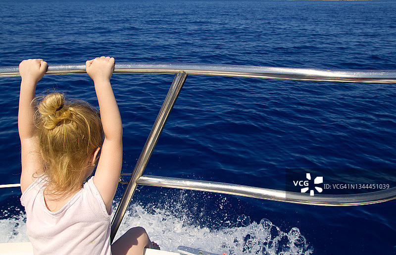 金发小女孩的后视镜在船上航行图片素材