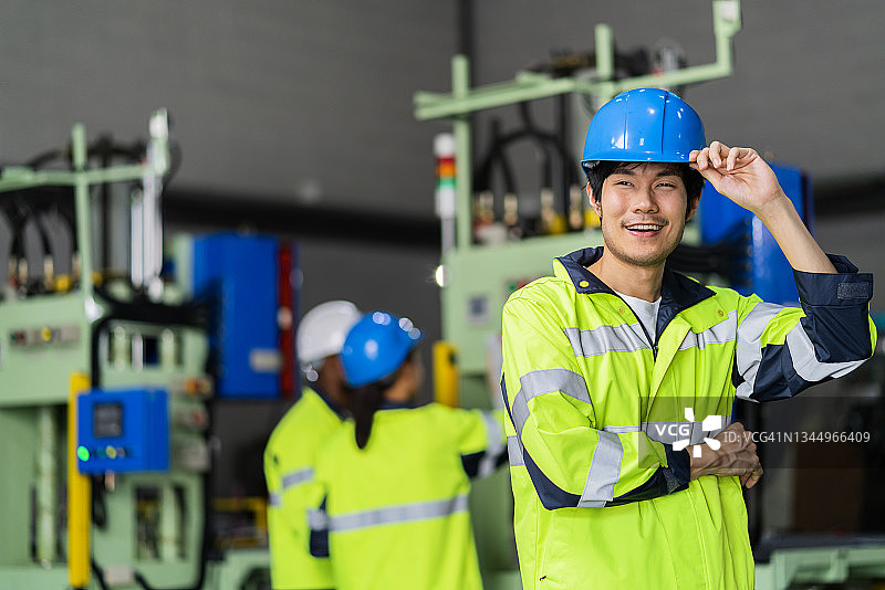 亚洲男技术员工业工程师在安全帽安全制服检查日期机器操作，而站在重工业制造工厂的工业概念图片素材