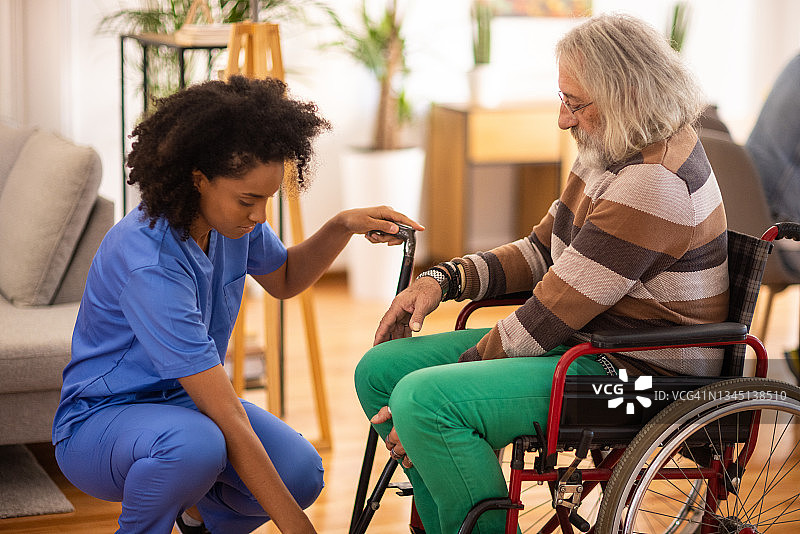 在养老院，女护士帮助老人从轮椅上站起来图片素材