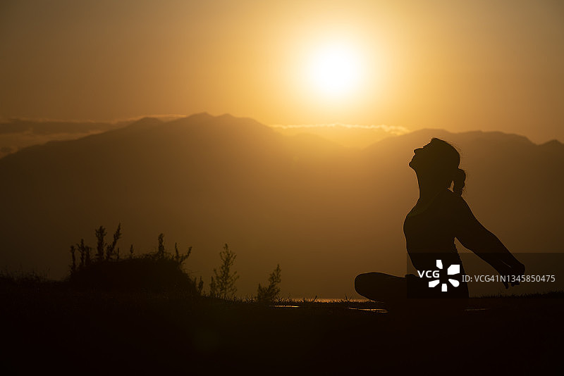 日落时练习瑜伽的成年妇女剪影照片图片素材