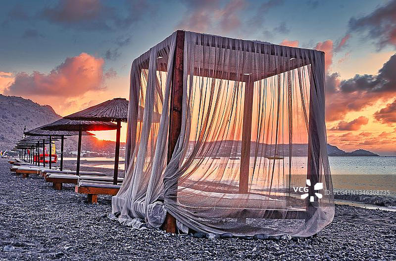遮阳伞和窗帘的沙滩躺椅，日出，海滩，罗德岛，希腊图片素材
