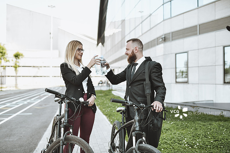 骑自行车上班的优雅商务夫妇用水祝酒图片素材