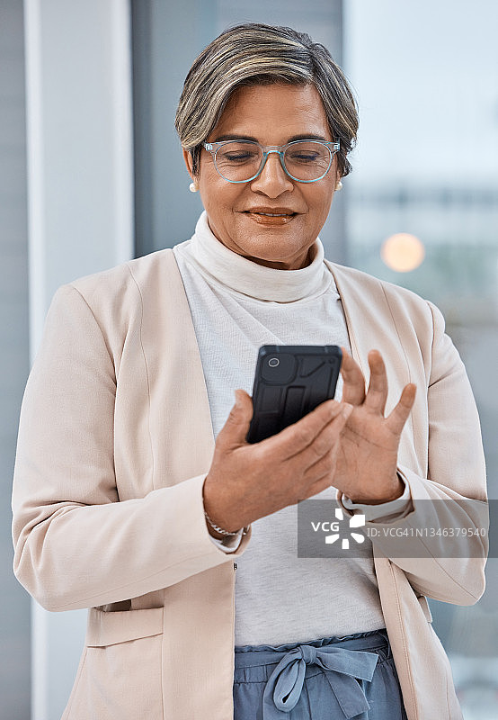 一个成熟的女商人在办公室里用手机图片素材
