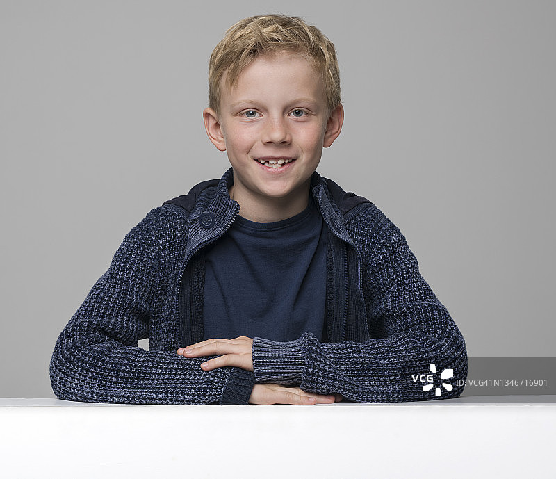 微笑的男孩靠在白色的聚苯乙烯板上图片素材