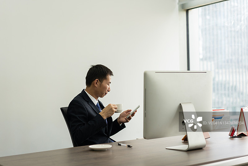亚洲男人在办公室使用智能手机图片素材