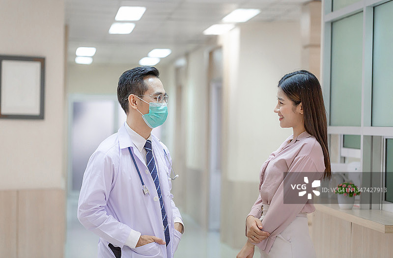 医生和病人站在医院里讨论着什么。医学和保健概念图片素材