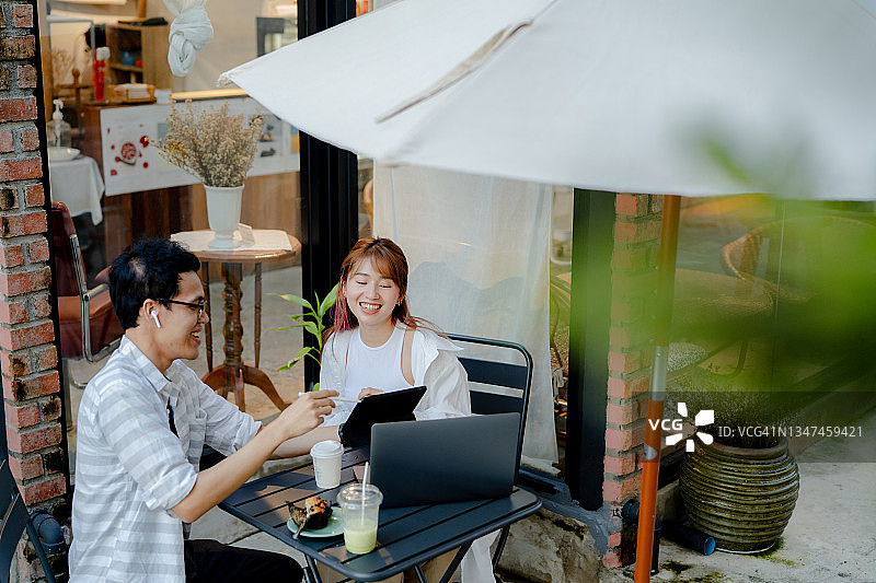 一对年轻夫妇在路边咖啡店用笔记本电脑一起工作图片素材