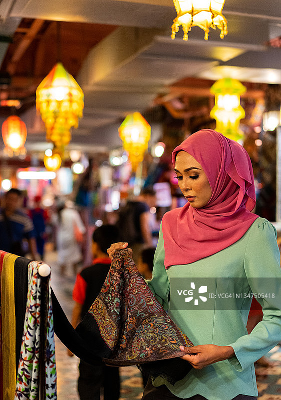 吸引年轻的马来西亚亚洲女人在斋月期间购物和准备节日。图片素材