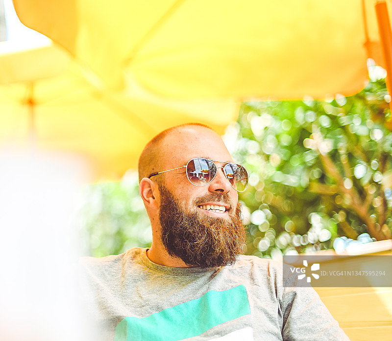 一名戴着太阳镜的男子在阳光明媚的黄色户外咖啡馆或餐厅休息图片素材