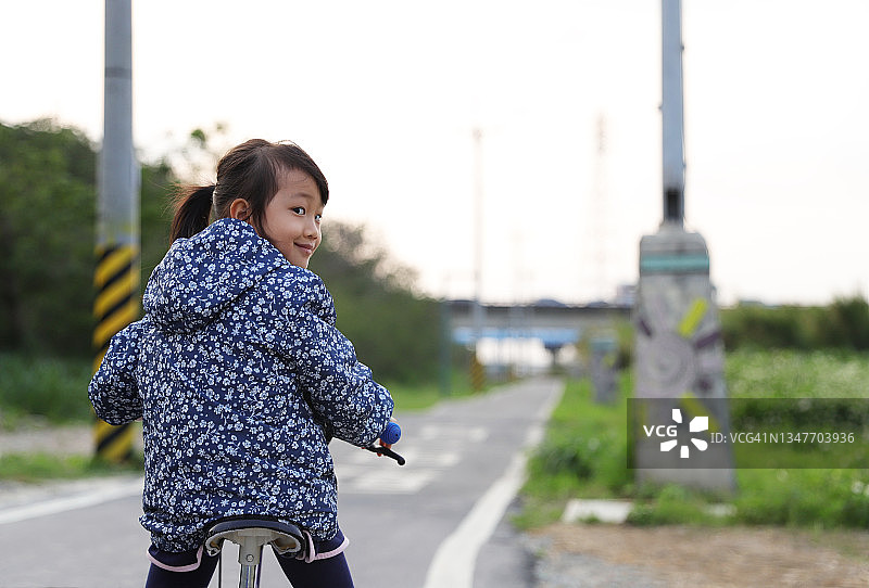 一个女孩在小路上骑自行车。图片素材
